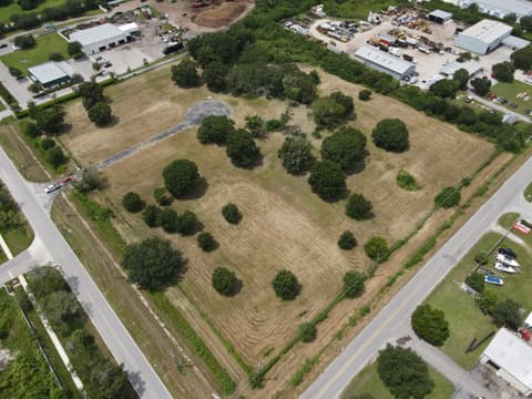 Aerial view of a large freshly bush-hogged field with scattered oak trees between roads in Tampa Bay